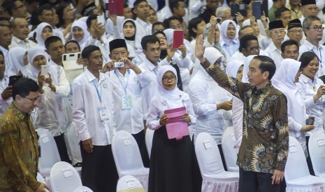 Presiden Joko Widodo (kanan) melambaikan tangan ke arah para guru yang hadir pada acara puncak Peringatan Hari Guru Nasional ke-21 Tahun 2015 di Istora Senayan, Jakarta, Selasa (24/11).