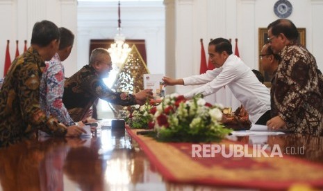 Presiden Joko Widodo (kanan) menerima buku laporan penyelenggaraan Pemilu Serentak tahun 2019 dari Ketua Komisi Pemilihan Umum (KPU) Arief Budiman dalam pertemuan di Istana Merdeka, Jakarta, Senin (11/11/2019).