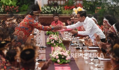 Presiden Joko Widodo (kanan) menerima map berisi saran dari perwakilan tokoh Papua Abisai Rollo (kiri) dalam pertemuan di Istana Negara, Jakarta, Selasa (10/9/2019).