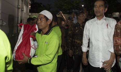 Presiden Joko Widodo (kanan) mengawasi pembagian sembako kepada warga di Gang Dahlia, Desa Cibuluh, Kabupaten Bogor, Jawa Barat, Kamis (8/7).