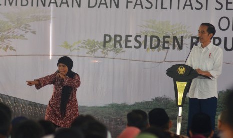 Presiden Joko Widodo (kanan) menyaksikan warga yang tampil memperagakan silat saat acara penyerahan sertifikat hak atas lahan tanah di lapangan Pemerintahan Kota Tasikmalaya, Jawa Barat, Jumat (9/6). 