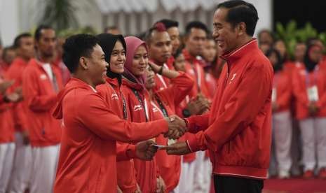 Presiden Joko Widodo (kanan) menyalami dan memberikan buku tabungan kepada lifter Eko Yuli Irawan (kiri) saat pemberian bonus kepada atlet peraih medali di Istana Negara, Jakarta, Minggu (2/9). Pemerintah memberikan bonus kepada para atlet yang berhasil meraih medali dalam ajang Asian Games 2018.