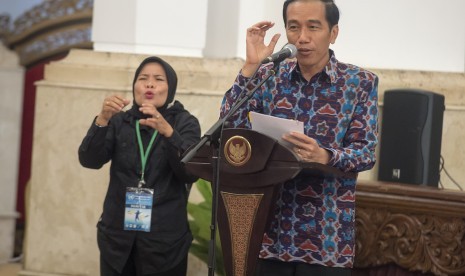 Presiden Joko Widodo (kanan) menyampaikan sambutannya dengan diterjemahkan ke dalam bahasa isyarat oleh petugas (kiri) pada acara puncak peringatan Hari Disabilitas Internasional Tahun 2015 di Istana Negara, Jakarta, Kamis (3/12).