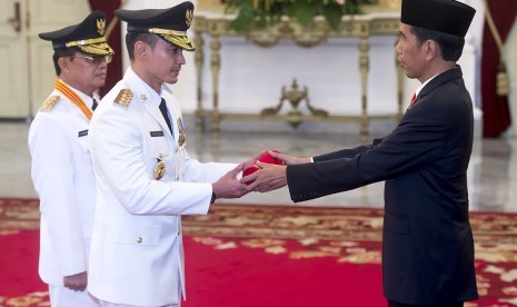 Presiden Joko Widodo (kanan) menyerahkan petikan Keppres kepada pasangan Gubernur dan Wakil Gubernur terpilih Jambi, Zumi Zola Zulkifli (tengah) dan Fachrori Umar (kiri) di Istana Merdeka, Jakarta, Jumat (12/2).