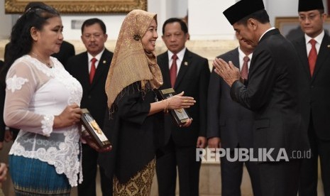 Presiden Joko Widodo (kanan) menyerahkan plakat anugerah gelar pahlawan nasional kepada ahli waris KH Masjkur di Istana Negara, Jakarta, Jumat (8/11/2019).