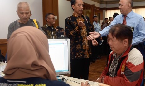 Presiden Joko Widodo (kedua kanan berdiri) berbincang dengan petugas pajak saat melayani wajib pajak yang ikut serta dalam program Pengampunan Pajak di Kantor Pelayanan Pajak Gabungan di Jalan M.I. Ridwan Rais, Jakarta, Rabu (28/9). 