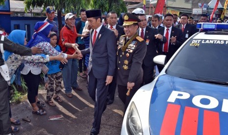 Presiden Joko Widodo (kedua kanan) didampingi Kapolri Jenderal Pol Tito Karnavian (kanan) menyapa warga ketika berjalan kaki menuju lokasi Upacara Parade dan Defile HUT ke-72 TNI Tahun 2017 di Dermaga Indah Kiat, Cilegon, Banten Kamis (5/10). 