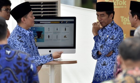 Presiden Joko Widodo (kedua kanan) didampingi Ketua Umum Dewan Pimpinan Nasional Korpri, Zudan Arif Fakhrulloh (kedua kiri) meninjau stan toko online KORPRI disela-sela peringatan HUT ke-45 KORPRI di Monumen Nasional, Jakarta, Selasa (29/11). 