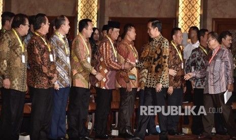 Presiden Joko Widodo (kedua kanan) didampingi Menko Perekonomian Darmin Nasution (kanan) menyapa kepala daerah yang hadir dalam Pembukaan Rapat Koordinasi Nasional Pengendalian Inflasi Tahun 2018 di Jakarta, Kamis (26/7). 