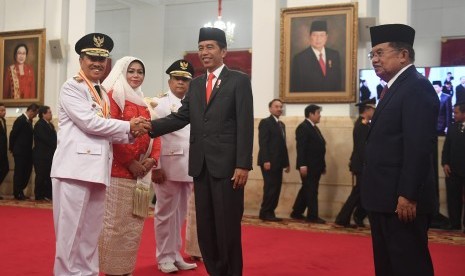 Presiden Joko Widodo (kedua kanan) didampingi Wakil Presiden Jusuf Kalla (kanan) berjabat tangan dengan Gubernur Riau yang baru dilantik Syamsuar (kiri) dan Wakil Gubernur Riau Edi Natar Nasution (ketiga kiri) di Istana Negara, Jakarta (20/2).