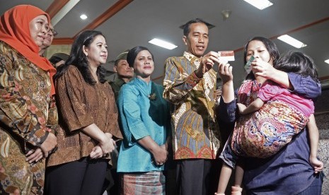 Presiden Joko Widodo (kedua kanan) memberi Kartu Indonesia Sehat (KIS), Kartu Indonesia Pintar (KIP) dan Kartu Keluarga Sejahtera (KKS) secara simbolis pada warga yang berhak.