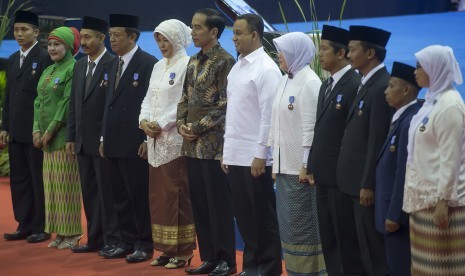 Presiden Joko Widodo (keenam kiri) dan Mendikbud Anies Baswedan (keenam kanan) berfoto bersama perwakilan guru penerima Satyalancana Pendidikan pada acara puncak Peringatan Hari Guru Nasional ke-21 Tahun 2015 di Istora Senayan, Jakarta, Selasa (24/11). 