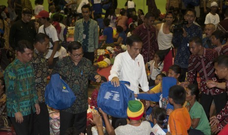 Presiden Joko Widodo (ketiga kiri) bersama Bupati Klungkung I Nyoman Suwirta (kiri) dan Mensesneg Pramono Anung (kedua kiri) memberi bantuan kepada para pengungsi Gunung Agung di GOR Suwecapura, Klungkung, Bali, Selasa (26/9).