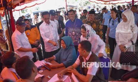 Presiden Joko Widodo (ketiga kiri) bersama Menteri PUPR Basuki Hadimuljono (kiri) berbincang dengan warga yang melakukan pencairan dana bantuan korban terdampak gempa di Dusun Pedamekan, Desa Belanting, Kecamatan Sambelia, Lombok Timur, NTB, Kamis (18/10/2018).