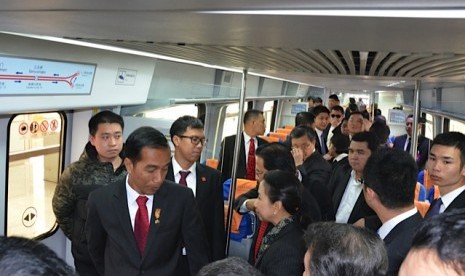 Presiden Joko Widodo (kiri) berbincang dengan Menteri BUMN Rini Soemarmo (kanan) dalam kereta api bawah tanah (subway) saat tiba di terminal 3 Bandara Internasional Capital Beijing, di Beijing, Kamis (26/3).