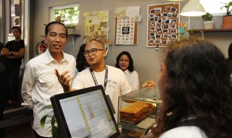 Presiden Joko Widodo (kiri) bersama Ibu Negara Iriana (ketiga kiri) mendengarkan penjelasan Pemilik Tuku Kopi Andanu Prasetyo (tengah) saat meminum kopi bersama keluarga di Tuku Kopi, Jakarta, Minggu (2/7). 