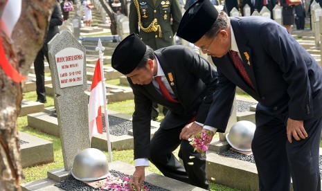 Presiden Joko Widodo (kiri) dan Wapres Jusuf Kalla (kanan) menabur bunga di makam mantan Ketua MPR Almarhum Taufiq Kiemas saat Upacara Ziarah Nasional di Taman Makam Pahlawan Nasional Utama Kalibata, Jakarta, Kamis (10/11).