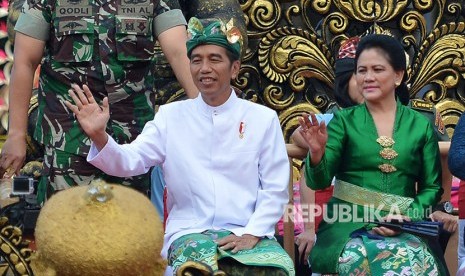 Presiden Joko Widodo (kiri) didampingi Ibu Negara Iriana Joko Widodo melambaikan tangan ketika mengikuti Pawai Pesta Kesenian Bali ke-40 di Denpasar, Bali, Sabtu (23/6).