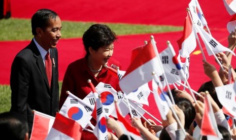 Presiden Joko Widodo (kiri) didampingi Presiden Korea Selatan Park Geun-hye menyapa para penyambut yang membawa bendera Korea Selatan dan bendera Indonesia di istana kepresidenan di Blue House di Seoul, South Korea, Senin (16/5). 