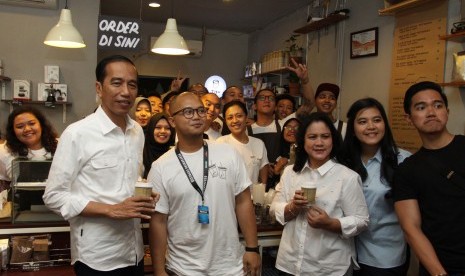 Presiden Joko Widodo (kiri), Ibu Negara Iriana (ketiga kanan) dan dua anak Kaesang Pangarep (kanan) dan Kahiyang Ayu (kedua kanan) didampingi Pemilik Tuku Kopi Andanu Prasetyo (kedua kiri) berfoto bersama saat meminum kopi di Tuku Kopi, Jakarta, Minggu (2/7). 