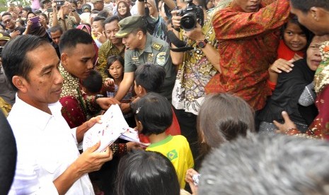 Presiden Joko Widodo (kiri) membagikan santunan kepada warga kurang mampu di Sempu, Cipare, Serang, Banten, Kamis (30/6). 