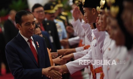 Presiden Joko Widodo (kiri) memberi ucapan selamat kepada anggota Pasukan Pengibar Bendera Pusaka (Paskibraka) usai upacara pengukuhan di Istana Negara, Jakarta, Kamis (15/8/2019).