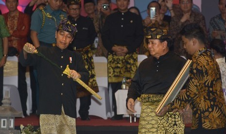 Presiden Joko Widodo (kiri) mendapat cendera mata dari Ketua Umum Ikatan Pencak Silat Indonesia (IPSI), Prabowo Subianto (kedua kanan) saat penutupan Kejuaraan Pencak Silat Internasional di GOR Lila Bhuana, Denpasar, Bali, Kamis (8/12).