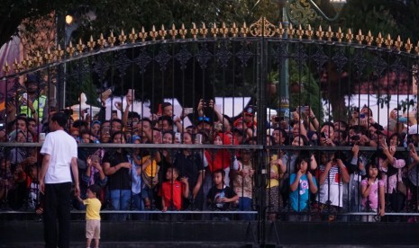 Presiden Joko Widodo (kiri) mengasuh cucunya, Jan Ethes Sri Narendra sambil menyapa warga di depan gerbang Istana Kepresidenan Yogyakarta pada Minggu sore (31/12). Presiden menunggu momen pergantian tahun dengan mengajak warga masuk ke istana dan menikmati kuliner tradisional.