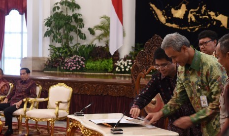 Presiden Joko Widodo (kiri) menyaksikan penandatanganan kerja sama fasilitas Kemudahan Investasi Langsung Konstruksi (KLIK) oleh Gubernur Jawa Tengah Ganjar Pranowo di Istana Negara, Jakarta, Senin (22/2). 