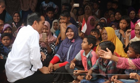 Presiden Joko Widodo (kiri) menyapa anak-anak korban gempa saat mengunjungi tempat pengungsian sementara di Desa Meurah Dua, Kecamatan Meureudu, Pidie Jaya, Aceh, Jumat (9/12). 