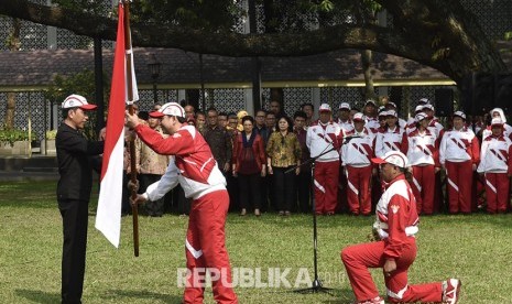 Presiden Joko Widodo (kiri) menyerahkan bendera Merah Putih kepada Ketua Kontingen Indonesia SEA Games XXIX Malaysia Aziz Syamsuddin (kedua kiri) saat upacara pelepasan di halaman Kompleks Istana Kepresidenan, Jakarta, Senin (7/8).