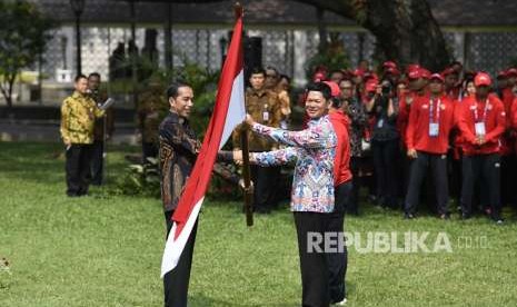 Presiden Joko Widodo (kiri) menyerahkan bendera Merah Putih kepada Ketua Inapgoc Raja Sapta Oktohari (kanan) saat upacara pelepasan kontingen Indonesia untuk Para Games ke-3 Tahun 2018 di halaman tengah Istana Kepresidenan, Jakarta, Selasa (2/10).