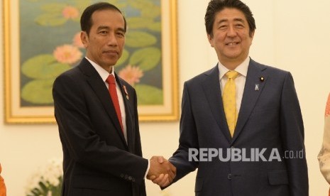 Presiden Joko Widodo (kiri tengah) berjabat tangan bersama Perdana Menteri Jepang Shinzo Abe saat kunjungan kenegaraan di Istana Bogor, Jawa Barat, Ahad (15/1)