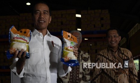 Presiden Joko Widodo (kirii) bersama Kepala Bulog Budi Waseso (kiri) menunjukkan beras kemasarn Bulog saat mengecek stok beras di Kompleks Pergudangan Bulog, Jakarta, Kamis (10/1/2019).