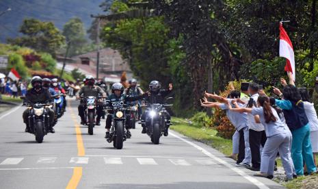 Presiden Joko Widodo melambaikan tangannya ke arah warga saat naik motor custom miliknya dari Sibisa di Kabupaten Toba menuju Parapat di Kabupaten Simalungun, Sumatera Utara, Rabu (2/2/2022). Salah satu agenda Presiden Joko Widodo hari ini di Sumatera Utara adalah meresmikan Jalan bypass (lingkar luar) Balige, Kabupaten Toba.