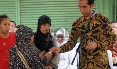 Presiden Joko Widodo membagikan Kartu Keluarga Sejahtera (KKS) kepada warga kurang mampu saat pembagian tiga jenis kartu sakti di wilayah Kampung Melayu, Jakarta Timur, Rabu (13/5).