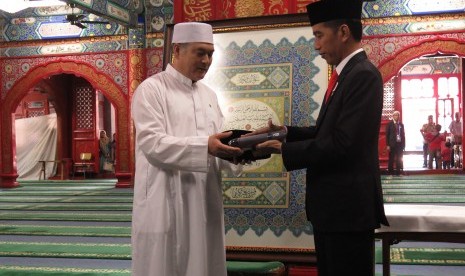 Presiden Joko Widodo memberikan cendera mata berupa songkok dan sarung kepada imam Masjid Niujie, Beijing, Ali Yang Gunjun, Minggu (14/5).