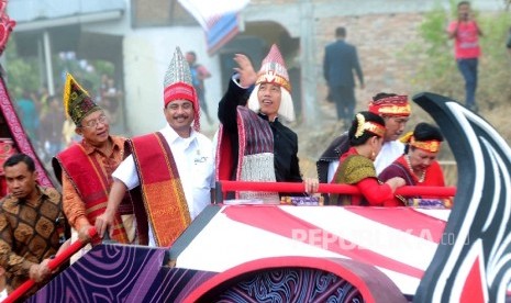 Presiden Joko Widodo mengenakan pakaian Adat Batak bersama Menteri Pariwisata Arief Yahya menyapa warga Balige saat Karnaval Kemerdekaan Pesona Danau Toba, Balige, Sumatra Utara, Ahad (22/8). (Republika/ Agung Supriyanto)