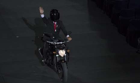 Presiden Joko Widodo mengendarai motor sambil melambaikan tangan saat pembukaan Asian Games ke-18 tahun 2018 di Stadion Utama Gelora Bung Karno, Jakarta, Sabtu (18/8).