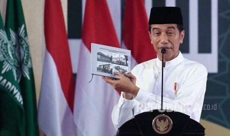 Presiden Joko Widodo menunjukkan buku ketika menghadiri milad satu abad Madrasah Muallimin dan Muallimat Muhammadiyah Yogyakarta di Yogyakarta, Kamis (6/12/2018). 