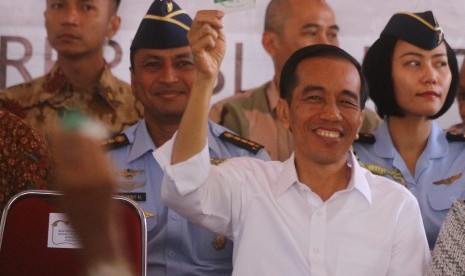 Presiden Joko Widodo menunjukkan Kartu Indonesia Sehat saat kunjungan kerja di Balaidesa Asrikaton, Pakis, Malang, Jawa Timur, Kamis (21/5). 