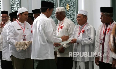 Presiden Joko Widodo menyerahkan sertifikat tanah wakaf kepada pengurus masjid, mushola dan pasantren seusai melaksanakan ibadah Jumat di Banda Aceh, Aceh, Jumat (14/12/2018).