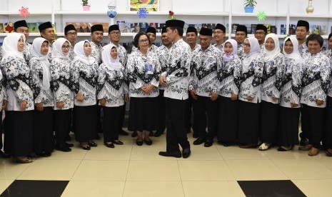 Presiden Joko Widodo (tengah) berjabat tangan dengan guru penerima penghargaan pada peringatan Hari Ulang Tahun ke-73 Persatuan Guru Republik Indonesia, di Stadion Pakansari, Jawa Barat, Sabtu (1/12/2018). 