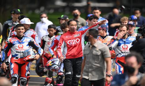 Presiden Joko Widodo (tengah) berjalan bersama para pembalap MotoGP sebelum melepas parade Moto GP di depan Istana Merdeka, Jakarta, Rabu (16/3/2022).