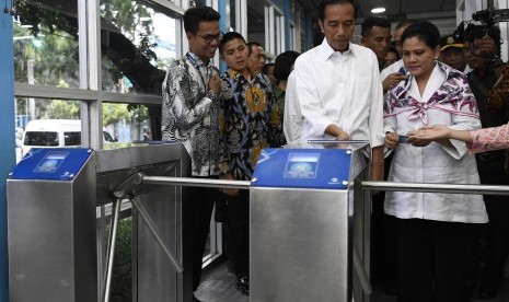 Presiden Joko Widodo (tengah) bersama Ibu Negara Iriana Joko Widodo (kanan) bersiap menaiki bus Transjakarta menuju Stasiun MRT Bundaran Hotel Indonesia di Jakarta, Kamis (21/3/2019).