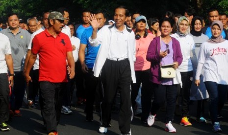 Presiden Joko Widodo (tengah) bersama Ibu Negara Iriana (keempat kanan), dan Wali Kota Surakarta FX Hadi Rudyatmo (kedua kiri) melakukan jalan santai pada hari bebas kendaraan di Solo, Jawa Tengah, Minggu (16/10). 