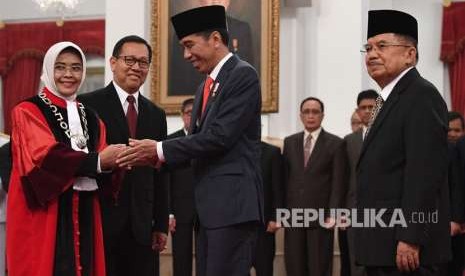 Presiden Joko Widodo (tengah) dan Wakil Presiden Jusuf Kalla (kanan) memberi ucapan selamat kepada Hakim Mahkamah Konstitusi Enny Nurbaningsih (kiri) seusai pelantikan di Istana Negara, Jakarta, Senin (13/8). 