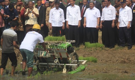 Presiden Joko Widodo (tengah) didampingi Gubernur Jawa Barat, Ahmad Heryawan (ketiga Kanan) bersama Menteri Pertanian, Andi Amran Sulaiman (kedua Kanan) dan Menteri PU - Pera, Basuki Hadimoeljono (kiri) melihat penanaman padi dengan mesin tanam (rice trans