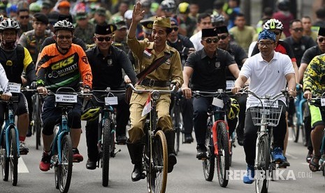 Presiden Joko Widodo (tengah) didampingi Gubernur Jawa Barat Ridwan Kamil (kanan) menyapa warga ketika mengikuti kegiatan sepeda bersama dengan tema Bandung Lautan Sepeda di Bandung, Jawa Barat, Sabtu (10/11)