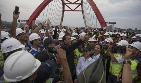 Presiden Joko Widodo (tengah) didampingi Ibu Negara Iriana Joko Widodo, Menteri BUMN Rini Soemarno bersama para pekerja proyek berswafoto usai meresmikan pengoperasian tujuh ruas jalan tol Trans Jawa di Jembatan Kalikuto, Kendal, Jawa Tengah, pada 20 Desember 2018. 